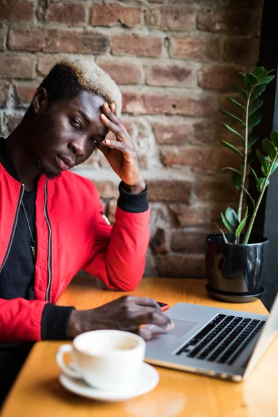 Potret pria sedih dengan ponsel duduk di kafe menggunakan laptop — Stok Foto