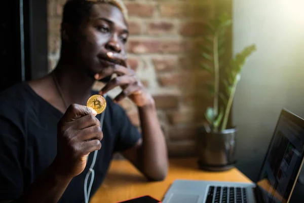 Afro american młodzieńca z bitcoin w ręce z przodu laptopa w kawiarni — Zdjęcie stockowe