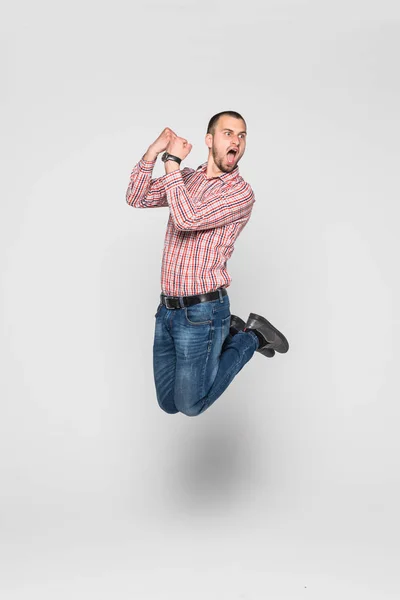 Imagem vertical de homem feliz em camisa e calça que saltando no estúdio. Retrato de comprimento total sobre fundo branco — Fotografia de Stock