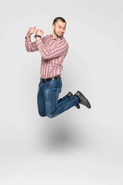 Image verticale de l'homme heureux en chemise et en jean qui saute en studio. Portrait pleine longueur sur fond blanc — Photo