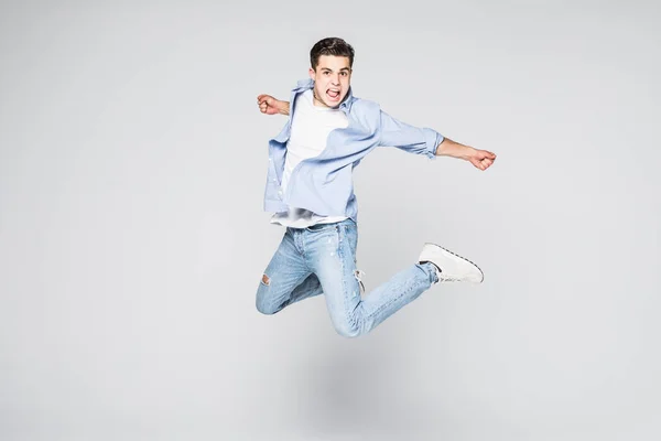 Foto completa de homem engraçado em camiseta casual e jeans correndo ou pulando no ar isolado sobre fundo branco — Fotografia de Stock