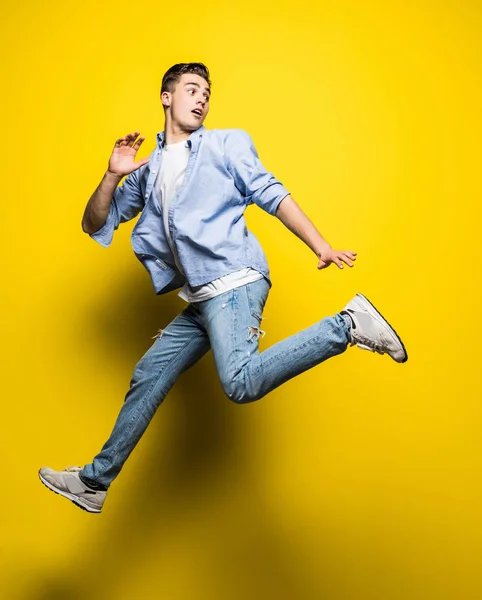 Hombre guapo casual vestido celebrando y saltando sobre fondo amarillo — Foto de Stock