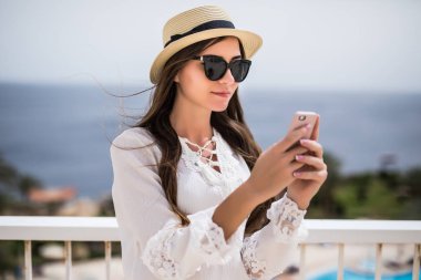 Yakın çekim yan görünüm gülümseyen bir genç kadın bir cep telefonu açık havada kullanma