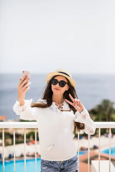 Temps de selfie. Jeune femme en chapeau d'été et lunettes de soleil, déjeuner sur une terrasse de lumière en plein air d'été en plein air au fond de la mer — Photo