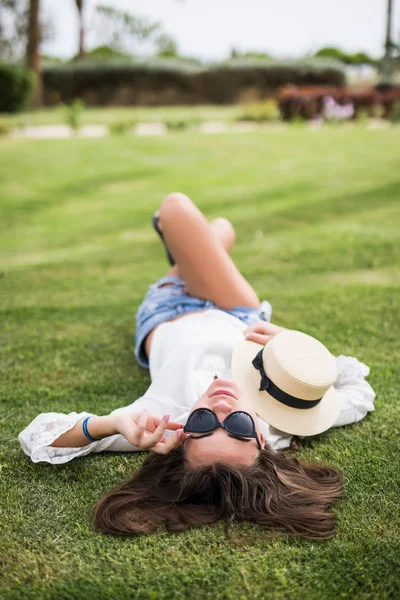 Красивая молодая женщина лежит на траве в солнечных очках в соломенной шляпе. Природная летняя концепция. Вид сверху . — стоковое фото