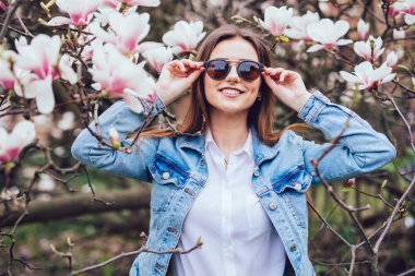 Şık casual kadın güneş gözlüğü çiçeği bahar ağaçları karşı