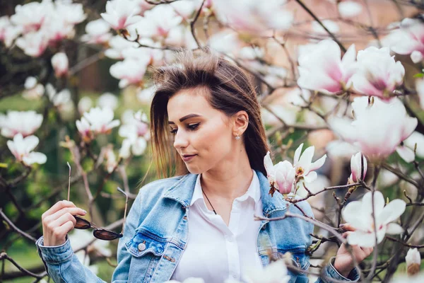 Giovane bella ragazza caucasica in un giardino di magnolia primaverile in fiore. La ragazza in giardino la mattina . — Foto Stock