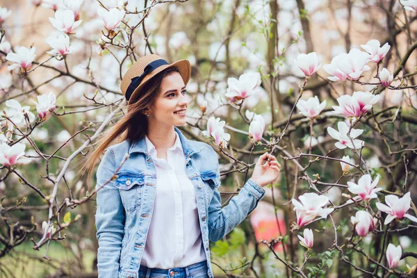 Ritratto di giovane bella donna in cappello di paglia in alberi di fiori primaverili . — Foto Stock