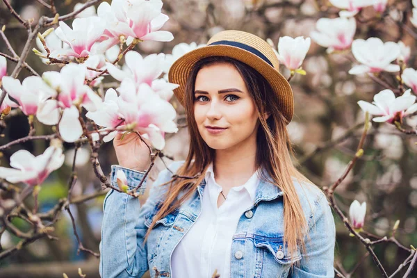 Bella ragazza di primavera in cappello estivo vicino albero di primavera fiore con fiori — Foto Stock