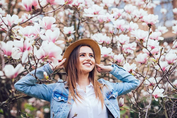 Ritratto all'aperto di una giovane bella donna con cappello estivo vicino magnolia albero con fiori . — Foto Stock