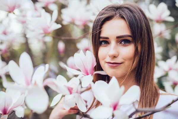Открытый портрет молодой красивой женщины возле дерева магнолия с цветами . — стоковое фото