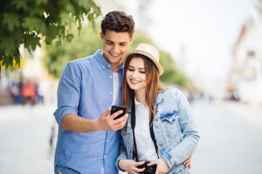 Mutlu genç çift app sokakta gezi turist telefon ekranına bakın