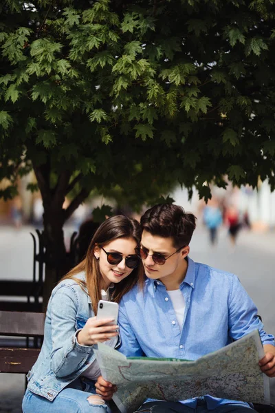 Mooie toeristische paar reizen met behulp van kaart en telefoon. Portret van glimlachende Man en jonge vrouw op straat, zoeken doellocatie op kaarten. Travel Concept. — Stockfoto