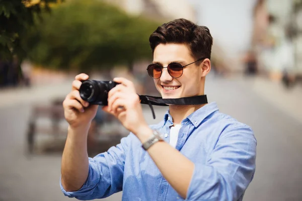 Portret van gelukkige jonge man, toeristen met camera in de nieuwe stad. — Stockfoto
