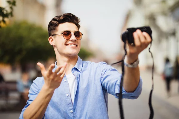 英俊的游客在度假时自拍。年轻男子微笑着在一个城市场景的相机。白种人。关于人、生活方式和技术的概念 — 图库照片