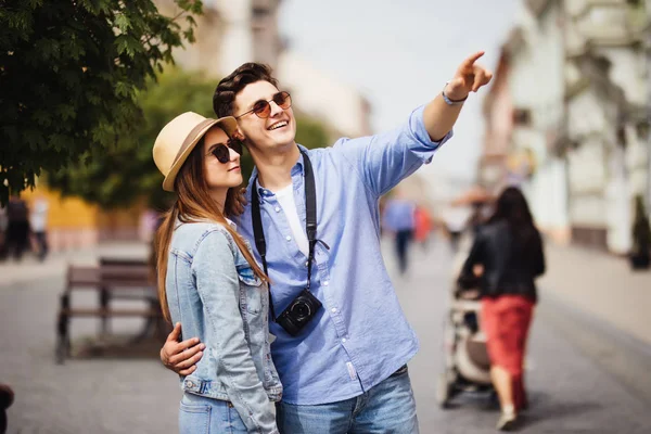 Feliz joven pareja de turistas de vacaciones en busca de una calle en un mapa y apuntando —  Fotos de Stock