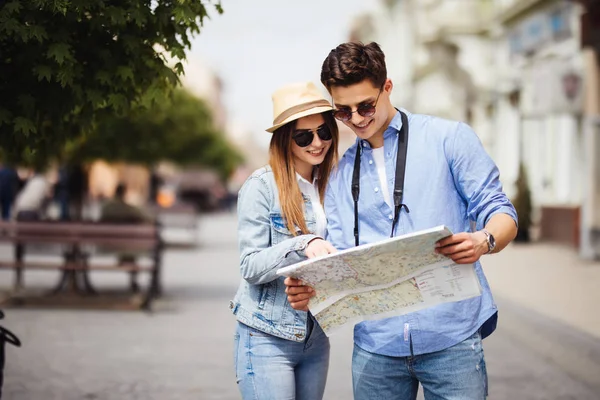 Lächelndes verliebtes Paar, das mit einer Landkarte in der Stadt unterwegs ist — Stockfoto