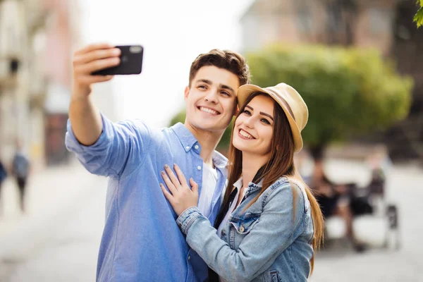 Felices turistas tomando selfie en la calle de la ciudad. Pareja tiene gran vocación veraniega en nuevo destino — Foto de Stock