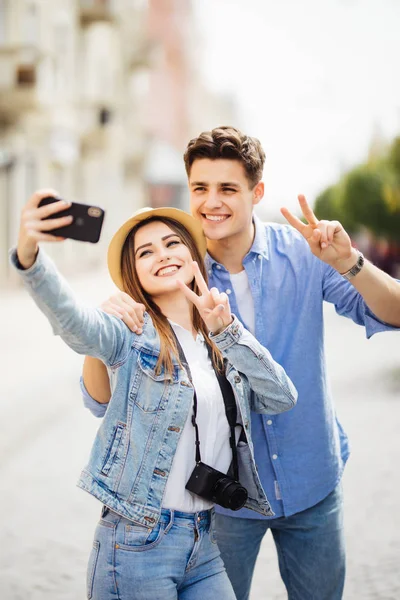 Un par de turistas fotografiando un selfie en una calle de la ciudad. Concepto de viaje — Foto de Stock