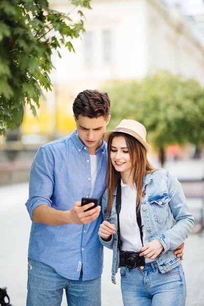 Retrato de jovem casal de turistas na cidade usando telefone celular na cidade nova . — Fotografia de Stock