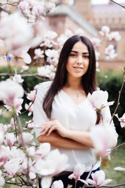 Bir çiçek açması bahar Manolya bahçede genç güzel bir beyaz kız.