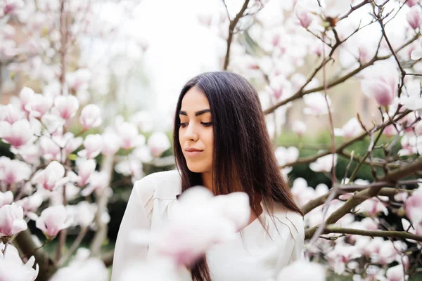 Ritratto all'aperto di una giovane bella donna vicino all'albero di magnolia con fiori . — Foto Stock