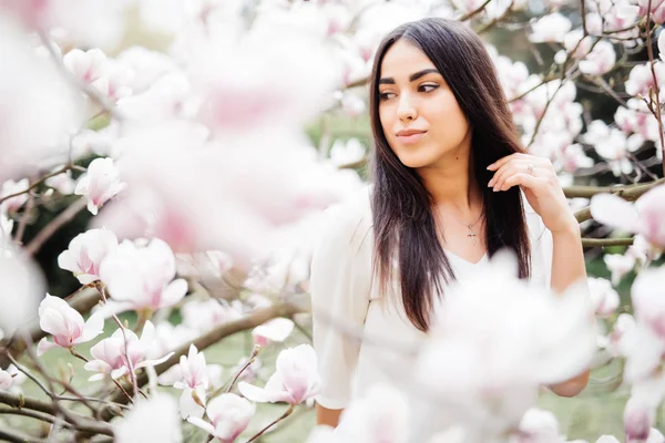 Bella ragazza in un giardino fiorito con magnolie. Magnolia fioritura, tenerezza . — Foto Stock