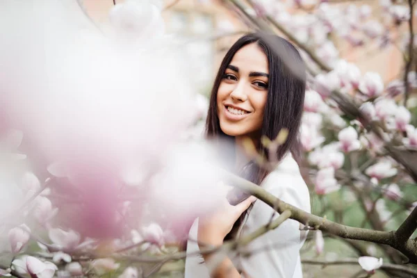 Egy fiatal gyönyörű nő virág, magnolia fa közelében szabadtéri portréja. — Stock Fotó