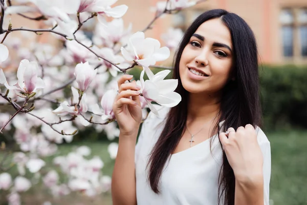 Fiatal gyönyörű lány kaukázusi tavasszal virágzó magnólia kert. — Stock Fotó