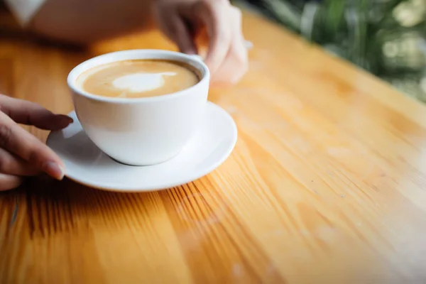 Zbliżenie na kobiece ręce trzymając kubek kawy w kawiarni — Zdjęcie stockowe