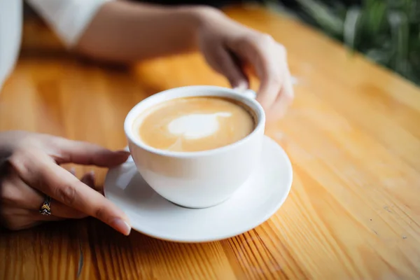 Close up de mãos femininas segurando xícara de café na cafetaria — Fotografia de Stock