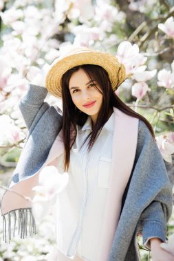 şapka ve güneş gözlüğü Manolya çiçek ağacıyla çevrili güzel genç kadın