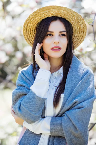 Jeune belle fille caucasienne en chapeau de paille dans un jardin de magnolia printemps florissant . — Photo