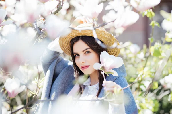 Jeune fille de beauté en chapeau près d'arbre magnolia en fleurs sur fond flou — Photo