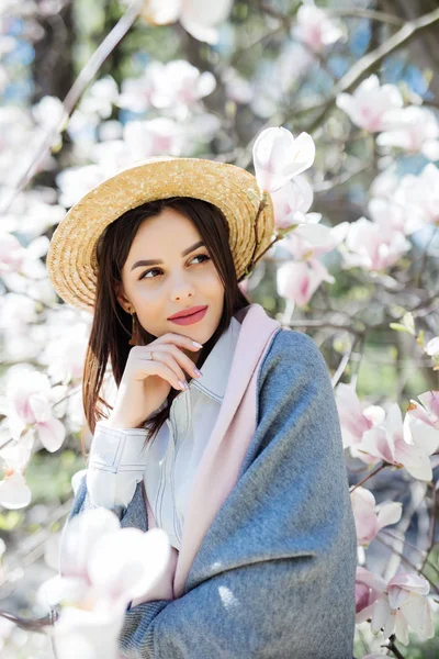 Jeune jolie fille en lunettes de soleil et chapeau de paille se détendre dans le beau jardin rose magnolias arbre — Photo
