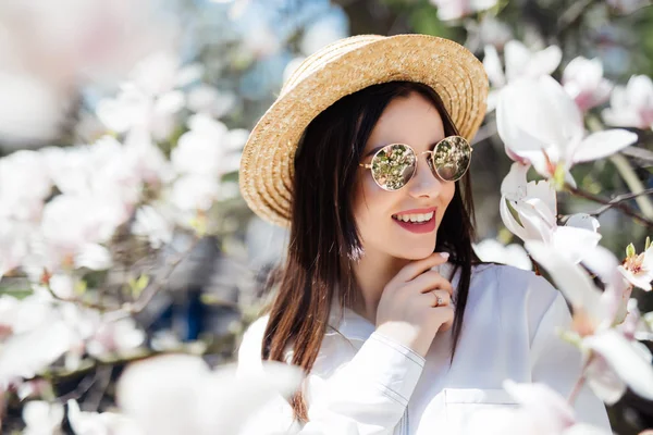 Napszemüveg és nyári kalap jelentő és fehér magnolia Park szép nő. Tavaszi idő háttér — Stock Fotó