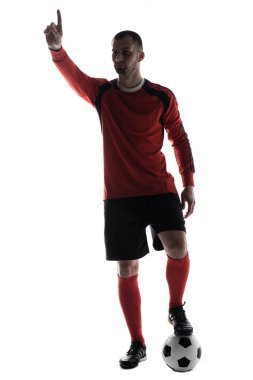 Beyaz arka plan üzerinde izole futbol topu ile parmak ile işaret genç futbolcu silüeti