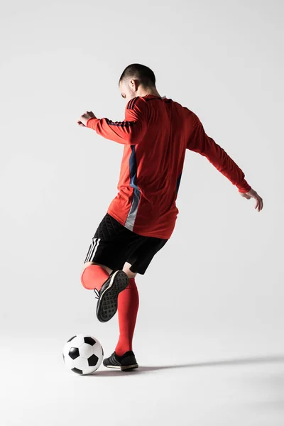 年轻足球运动员踢球剪影的后方看法在白色背景下被隔绝 — 图库照片