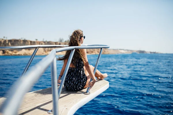 Молодая женщина лежит на роскошной яхте в море и смотрит на горизонт — стоковое фото