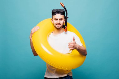 Yakışıklı delikanlı şişme sarı halkalı ve şnorkel göstermek izole üzerindeki yeşil renkli yukarı