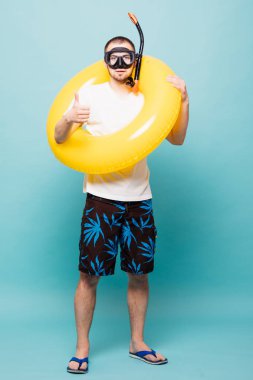 Tam uzunlukta yakışıklı delikanlı şişme sarı yüzüklü ve üzerinde yeşil arka plan izole aşınma şnorkel maskesi