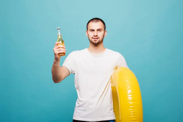 Bonito jovem vestindo anel inflável e segurando garrafa de cerveja isolada sobre fundo verde — Fotografia de Stock