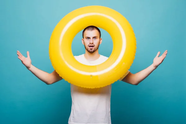 Retrato de un alegre hombre feliz mirando a través del anillo inflable aislado sobre fondo verde —  Fotos de Stock