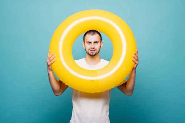 Retrato de un alegre hombre feliz mirando a través del anillo inflable aislado sobre fondo verde —  Fotos de Stock