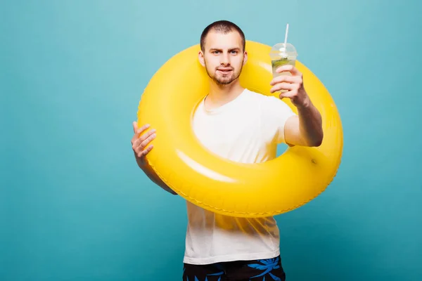 Yaz taze içkiyle üzerinde yeşil arka plan izole şişme yüzüklü genç adam — Stok fotoğraf