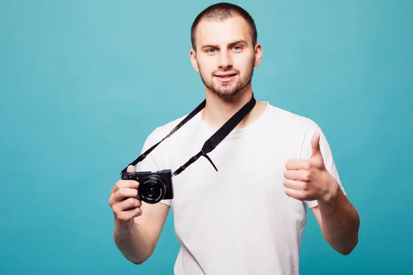 Imagen de joven fotógrafo guapo emocional sosteniendo cámara aislada sobre fondo de pared verde — Foto de Stock