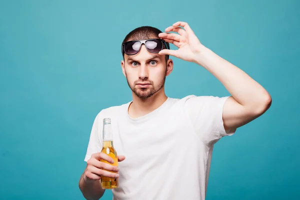 Retrato de um feliz verão jovem em óculos de sol homem segurando garrafas de cerveja isolado sobre fundo verde — Fotografia de Stock