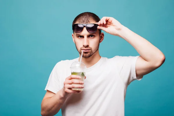 Genç adam güneş gözlüğü ve izole yeşil arka plan üzerinde beyaz t-shirt içme mojito yaz — Stok fotoğraf