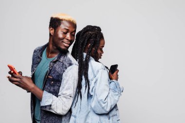 Arka arkaya cep telefonları beyaz arka plan üzerinde tutarak Afrikalı çift ayakta yan portresi