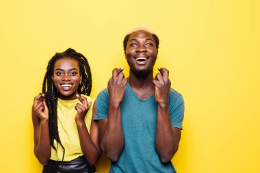 Heyecanlı bir genç Afrikalı çift birlikte ve çapraz parmak kadar beyaz bitti izole kopya alanı ayakta portresi